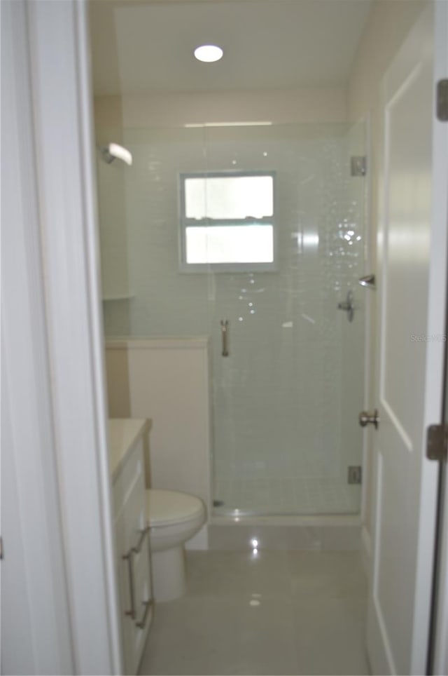 bathroom with toilet, tile flooring, and a shower with shower door