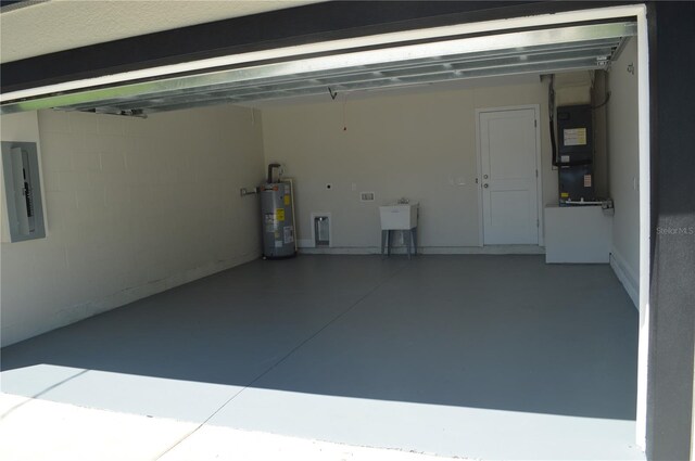 garage featuring water heater, sink, and heating utilities