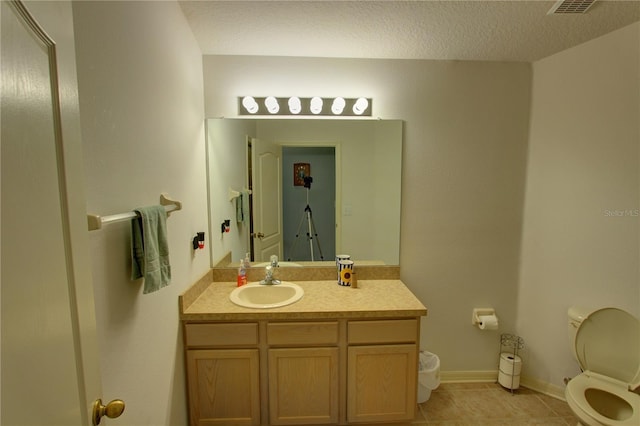 bathroom featuring a textured ceiling, tile flooring, toilet, and vanity