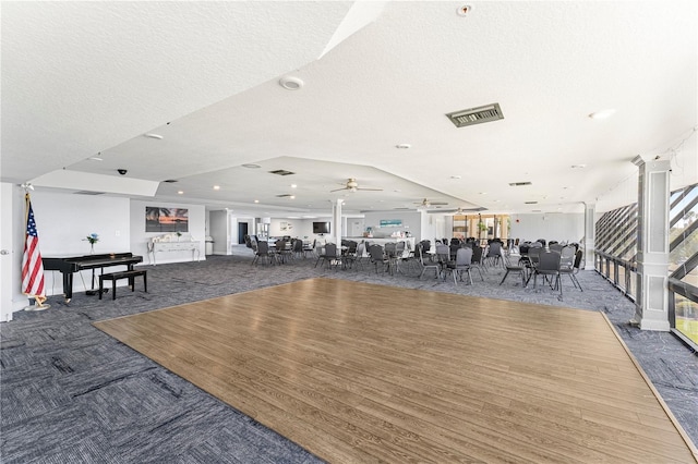 exercise room with ceiling fan, a wealth of natural light, a textured ceiling, and dark carpet