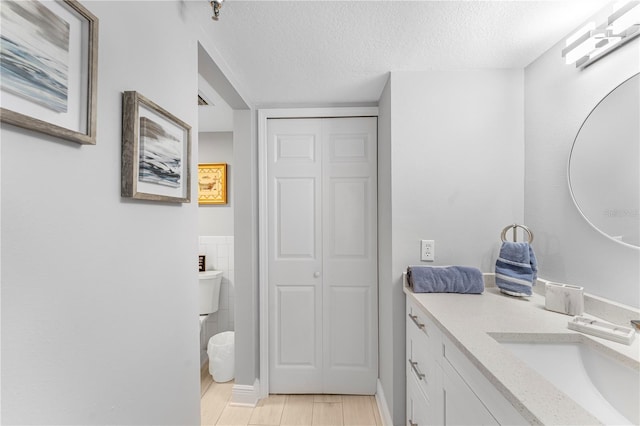 bathroom featuring vanity, a textured ceiling, and toilet