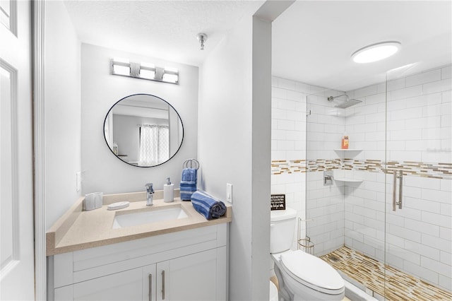 bathroom featuring walk in shower, vanity, toilet, and a textured ceiling