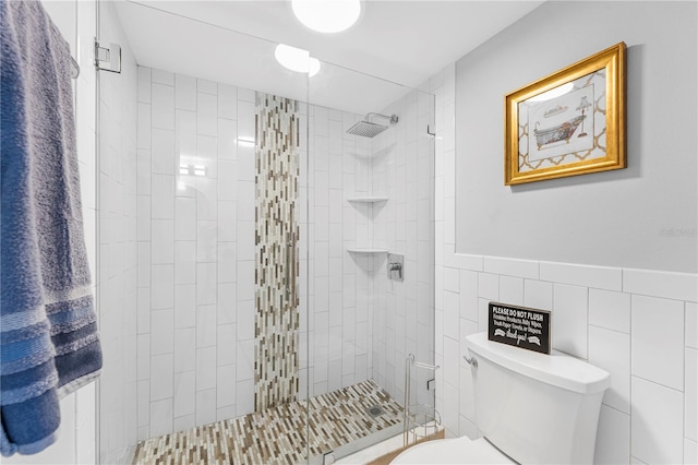 bathroom with toilet, a shower stall, tile walls, and wainscoting