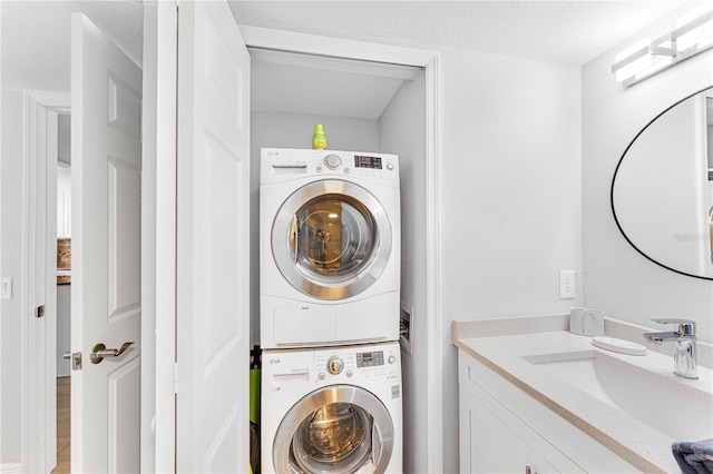 clothes washing area featuring stacked washing maching and dryer, sink, and a textured ceiling