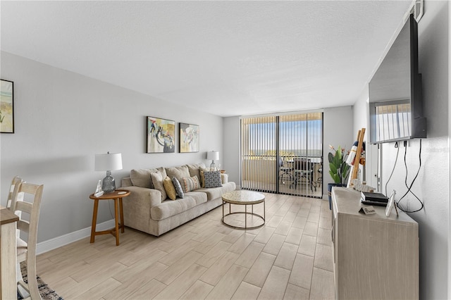 living area with a textured ceiling, light wood finished floors, expansive windows, and baseboards