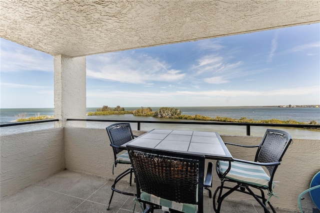 balcony with outdoor dining space and a water view