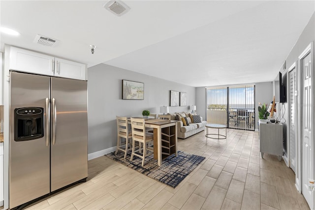 dining room with baseboards, floor to ceiling windows, visible vents, and wood tiled floor