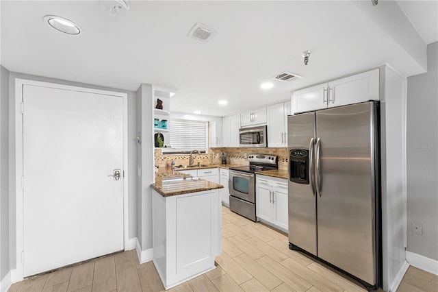 kitchen featuring white cabinetry, appliances with stainless steel finishes, open shelves, and a sink