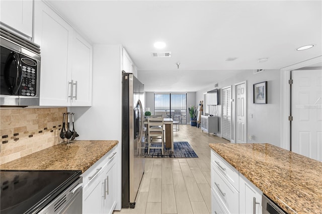 kitchen with appliances with stainless steel finishes, white cabinetry, light stone countertops, and decorative backsplash