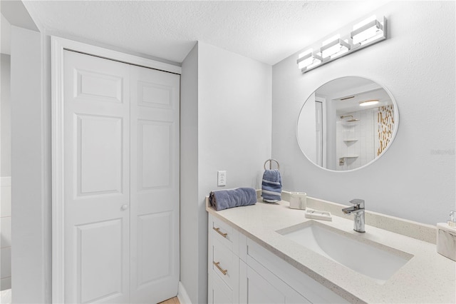 bathroom with a closet, walk in shower, a textured ceiling, and vanity