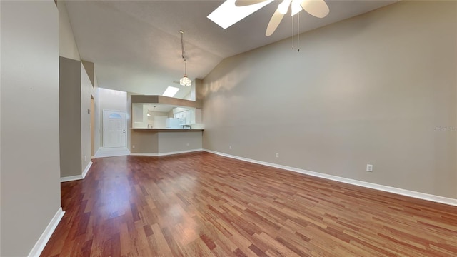 empty room with hardwood / wood-style floors, lofted ceiling with skylight, and ceiling fan