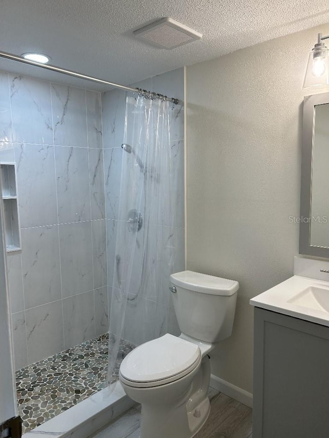 bathroom featuring vanity, walk in shower, a textured ceiling, toilet, and hardwood / wood-style flooring