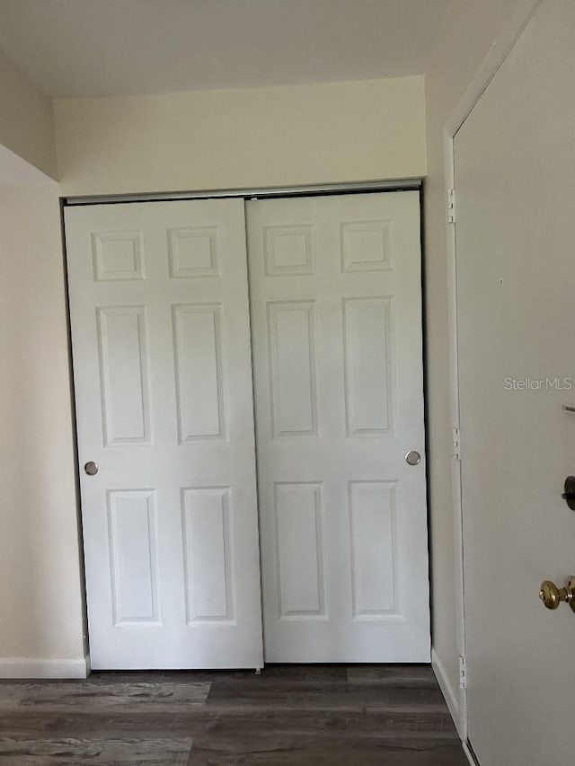 unfurnished bedroom with a closet and dark wood-type flooring