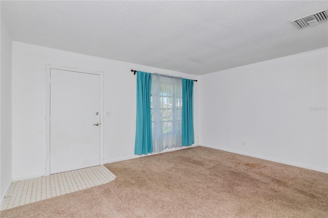 spare room with a textured ceiling and light colored carpet