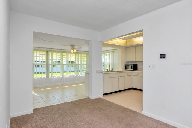 kitchen featuring light carpet, cream cabinets, ceiling fan, and sink