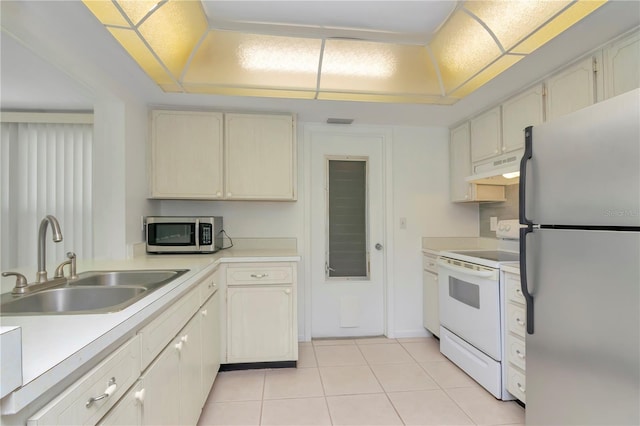 kitchen with a raised ceiling, appliances with stainless steel finishes, light tile floors, and sink