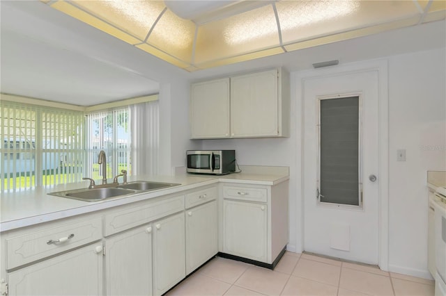 kitchen with light tile flooring, white cabinets, and sink