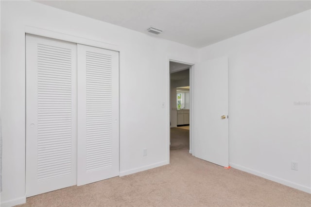 unfurnished bedroom with light colored carpet and a closet