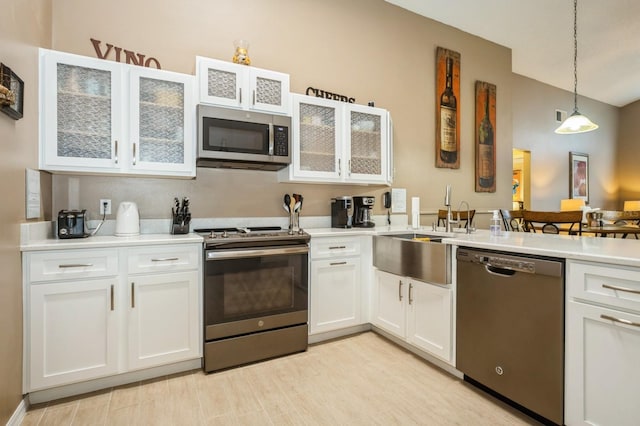 kitchen with white cabinetry, decorative light fixtures, appliances with stainless steel finishes, light hardwood / wood-style floors, and sink