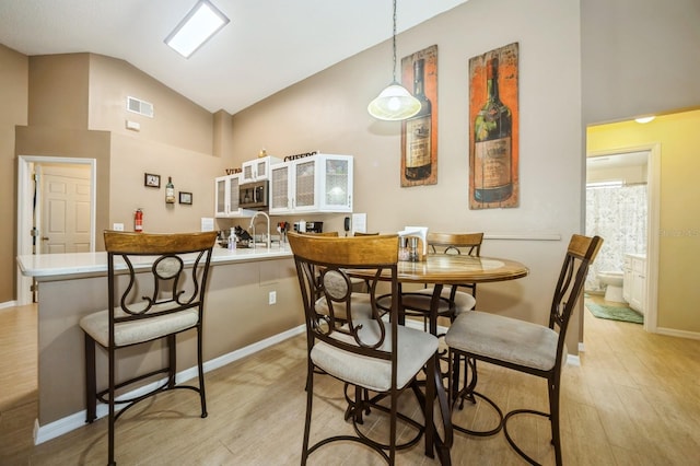 dining area featuring high vaulted ceiling and light hardwood / wood-style floors