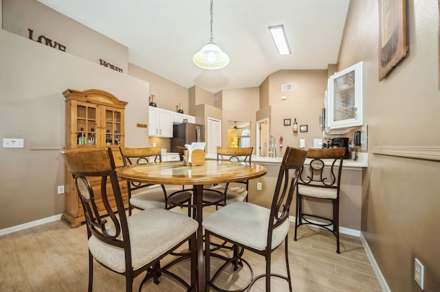 dining space featuring vaulted ceiling, light wood-type flooring, and sink