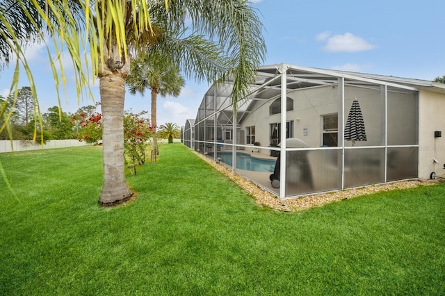 back of property featuring glass enclosure, a fenced in pool, and a lawn