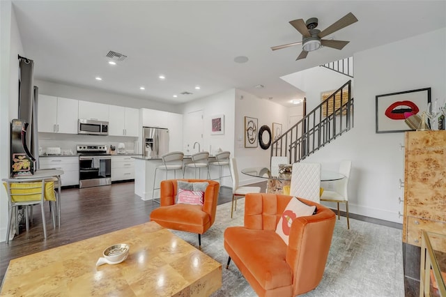 living room featuring ceiling fan and dark wood-type flooring