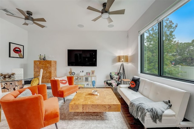 living room with dark wood-type flooring, ceiling fan, and a wealth of natural light