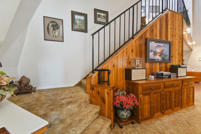 stairs featuring light carpet and wooden walls