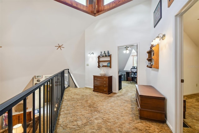 hallway with a skylight, carpet, and a high ceiling