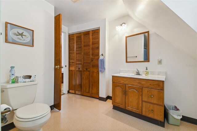 bathroom featuring vaulted ceiling, toilet, and large vanity