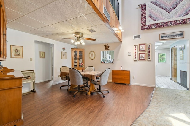 dining space with wood-type flooring, a drop ceiling, and ceiling fan