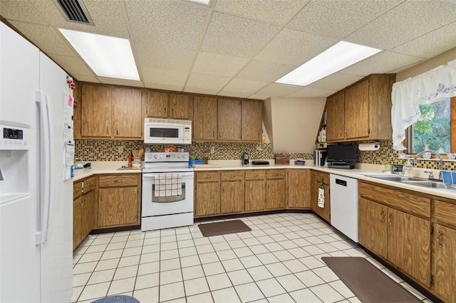 kitchen with white appliances, a drop ceiling, sink, light tile floors, and tasteful backsplash