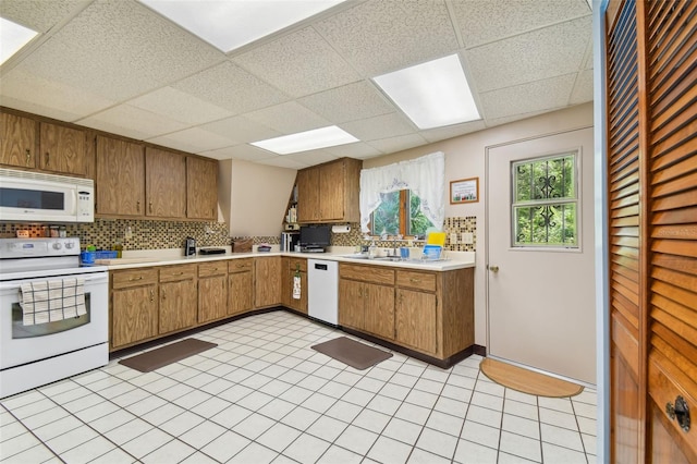 kitchen with white appliances, tasteful backsplash, a paneled ceiling, and light tile floors