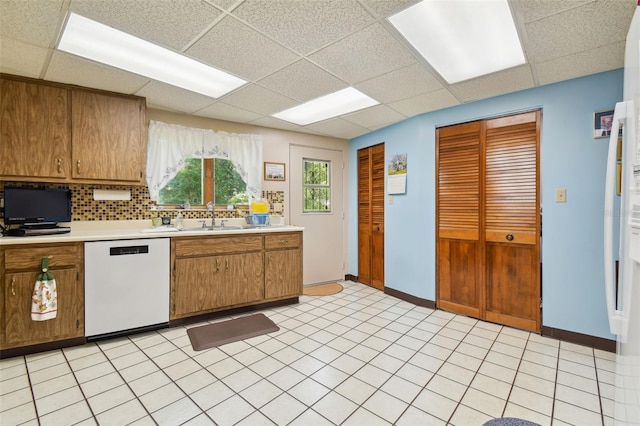 kitchen featuring a drop ceiling, sink, dishwasher, and light tile floors