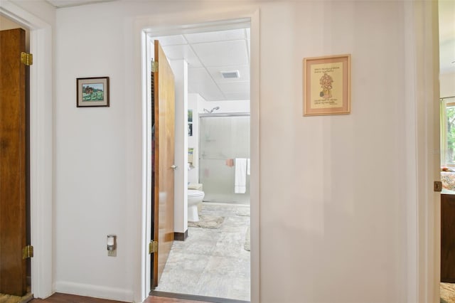 hallway with a drop ceiling and tile floors