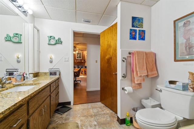 bathroom featuring a drop ceiling, toilet, tile floors, and vanity