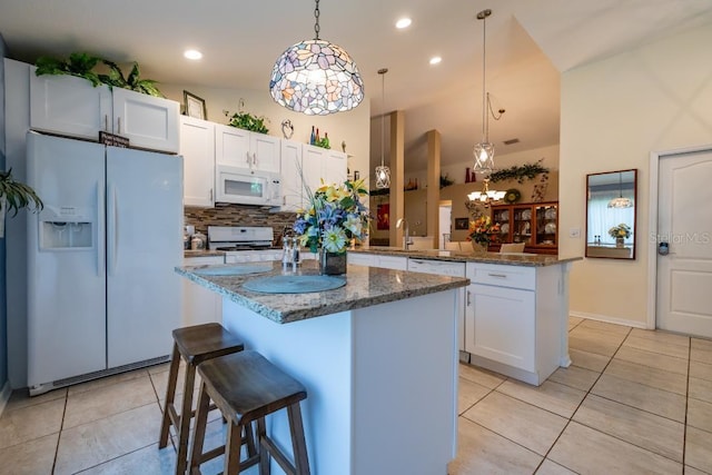 kitchen featuring kitchen peninsula, white appliances, pendant lighting, a kitchen island, and backsplash