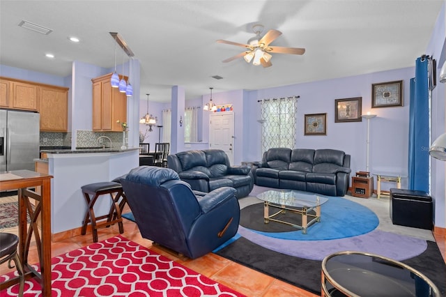 tiled living room with ceiling fan with notable chandelier and sink