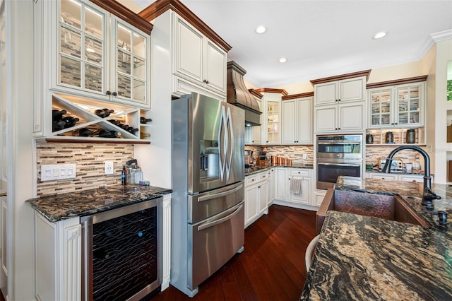 kitchen with beverage cooler, dark hardwood / wood-style floors, tasteful backsplash, dark stone countertops, and appliances with stainless steel finishes