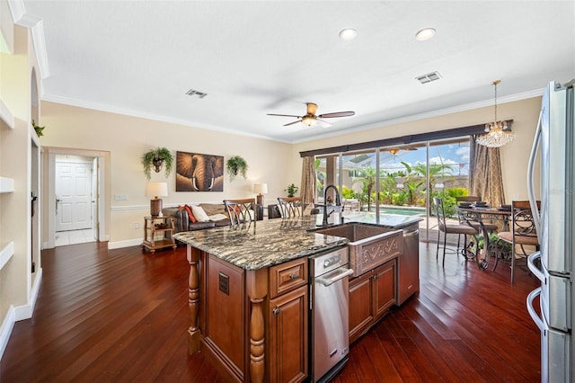 kitchen featuring dark wood-type flooring, an island with sink, ceiling fan with notable chandelier, and ornamental molding