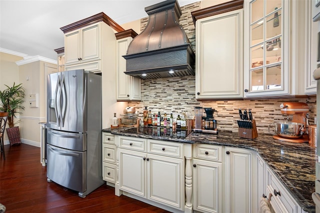 kitchen featuring dark hardwood / wood-style floors, custom exhaust hood, dark stone countertops, backsplash, and stainless steel fridge with ice dispenser