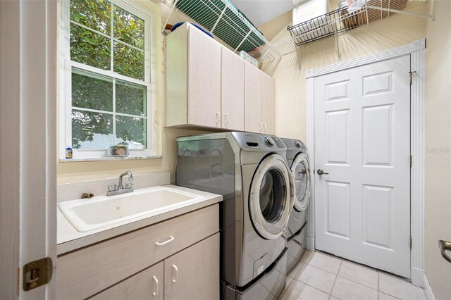 laundry area featuring sink, washing machine and dryer, light tile floors, and cabinets