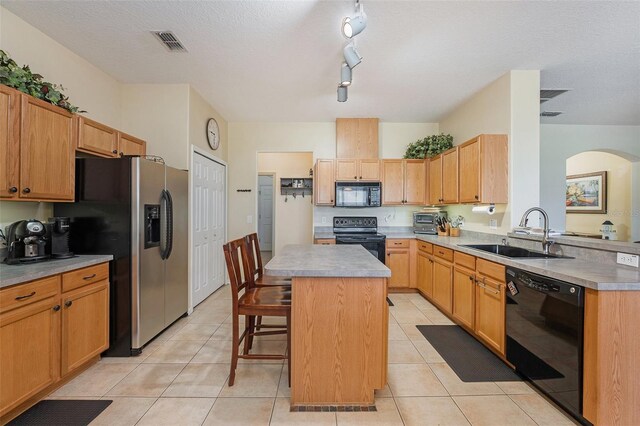 kitchen featuring a center island, rail lighting, a breakfast bar, black appliances, and sink