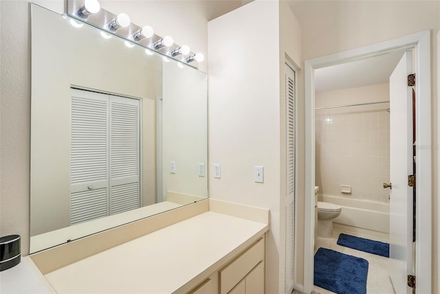 full bathroom with tiled shower / bath, toilet, tile floors, and vanity