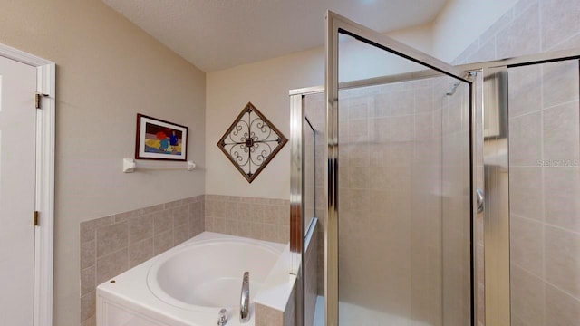 bathroom with a textured ceiling and separate shower and tub