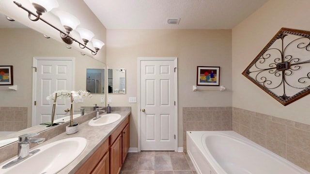 bathroom with double sink, tiled tub, tile floors, oversized vanity, and a textured ceiling