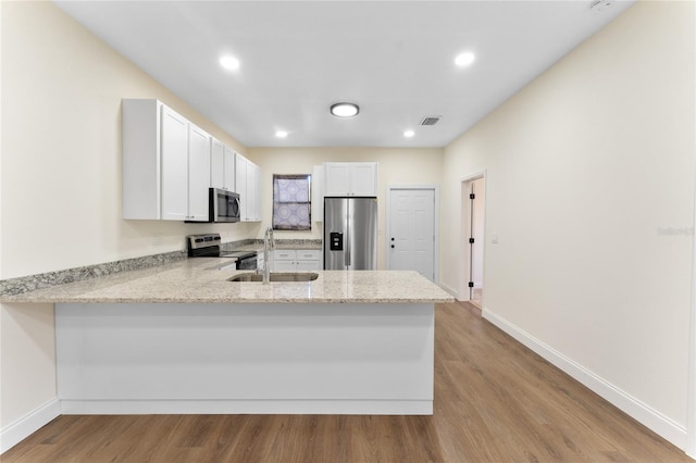 kitchen featuring kitchen peninsula, stainless steel appliances, light hardwood / wood-style floors, white cabinets, and sink