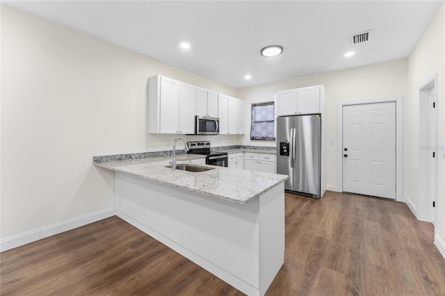 kitchen featuring light stone counters, white cabinets, stainless steel appliances, kitchen peninsula, and hardwood / wood-style flooring