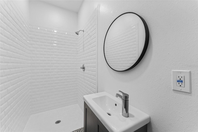 bathroom with vanity with extensive cabinet space and a tile shower